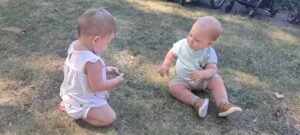 Dzieci oglądają szyszkę znalezioną w żłobkowym ogrodzie.