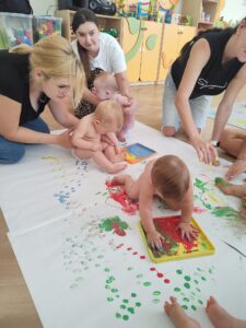 Dzieci odbijają rączki na dużej kartce papieru.