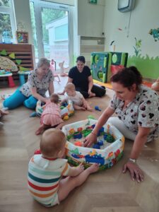 Dzieci bawią się piaskiem kinetycznym z ciociami.