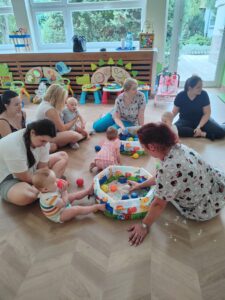 dzieci wraz z rodzicami bawią się piaskiem kinetycznym.