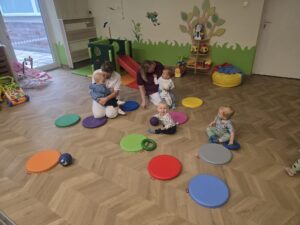 Ciocie bawią się z dziećmi na podłodze kolorowymi piłeczkami i ringo.