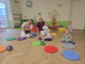 Dzieci siedzą na kolorowych krążkach. bawią się piłeczkami.