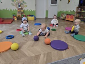 Dzieci siedzą na krążkach przypominających kropki.