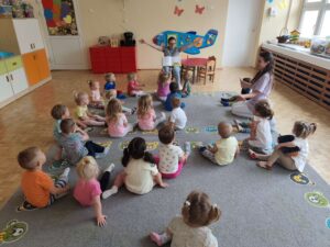 Czytanie dzieciom siedzącym na dywanie przez Panią bibliotekarkę.