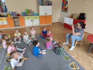 Czytanie dzieciom siedzącym na dywanie przez Panią bibliotekarkę.