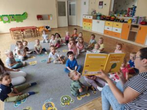 Czytanie dzieciom siedzącym na dywanie przez Panią bibliotekarkę.