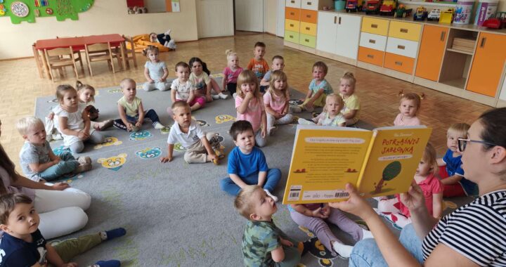Czytanie dzieciom siedzącym na dywanie przez Panią bibliotekarkę.