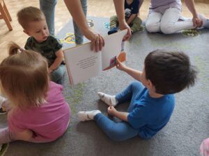 Czytanie dzieciom siedzącym na dywanie przez Panią bibliotekarkę.