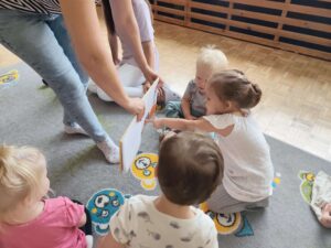 Czytanie dzieciom siedzącym na dywanie przez Panią bibliotekarkę.