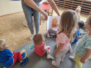 Czytanie dzieciom siedzącym na dywanie przez Panią bibliotekarkę.