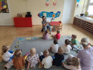 Czytanie dzieciom siedzącym na dywanie przez Panią bibliotekarkę.