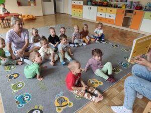 Czytanie dzieciom siedzącym na dywanie przez Panią bibliotekarkę.