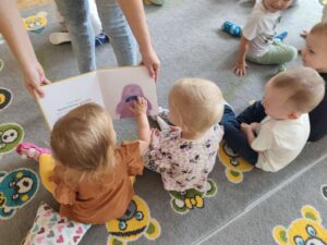 Czytanie dzieciom siedzącym na dywanie przez Panią bibliotekarkę.