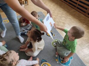 Czytanie dzieciom siedzącym na dywanie przez Panią bibliotekarkę.