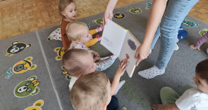 Czytanie dzieciom siedzącym na dywanie przez Panią bibliotekarkę.
