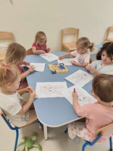 Dzieci przy stoliku wykonują pracę plastyczną z wykorzystaniem plasteliny