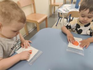 Dzieci przy stoliku wykonują pracę plastyczną