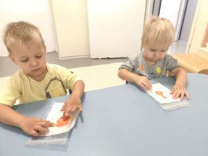 Dzieci przy stoliku wykonują pracę plastyczną