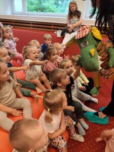 Dzieci podają rękę kukiełce smoka