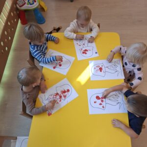 Dzieci ozdabiają kropkami kapelusz grzyba