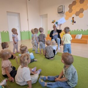 Czytanie dzieciom siedzącym na dywanie przez Panią bibliotekarkę.