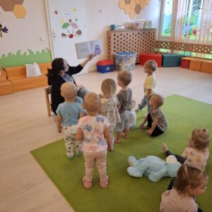 Czytanie dzieciom siedzącym na dywanie przez Panią bibliotekarkę.
