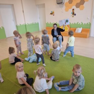 Czytanie dzieciom siedzącym na dywanie przez Panią bibliotekarkę.