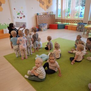 Czytanie dzieciom siedzącym na dywanie przez Panią bibliotekarkę.