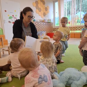 Czytanie dzieciom siedzącym na dywanie przez Panią bibliotekarkę.