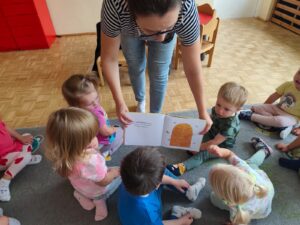 Czytanie dzieciom siedzącym na dywanie przez Panią bibliotekarkę.