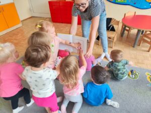 Czytanie dzieciom siedzącym na dywanie przez Panią bibliotekarkę.