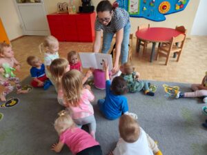 Czytanie dzieciom siedzącym na dywanie przez Panią bibliotekarkę.