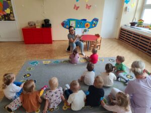 Czytanie dzieciom siedzącym na dywanie przez Panią bibliotekarkę.