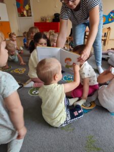 Czytanie dzieciom siedzącym na dywanie przez Panią bibliotekarkę.