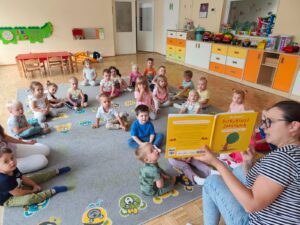 Czytanie dzieciom siedzącym na dywanie przez Panią bibliotekarkę.