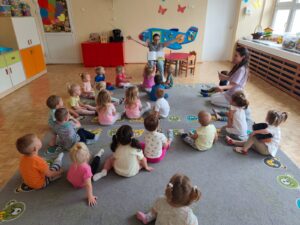 Czytanie dzieciom siedzącym na dywanie przez Panią bibliotekarkę.