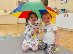Dwie dziewczynki uśmiechają się trzymając parasol