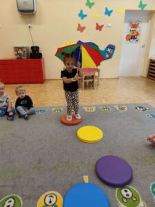 Dziewczynka z parasolem skacze po kolorowych kółkach