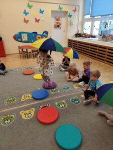 Dziewczynka z parasolem skacze po kolorowych kółkach