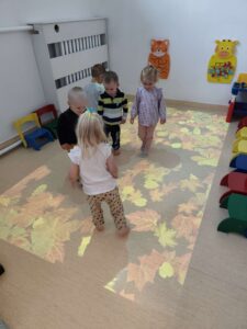 Dzieci bawią się na magicznym dywanie- biegają po jesiennych liściach