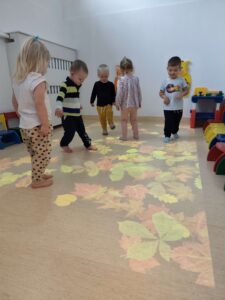 Dzieci bawią się na magicznym dywanie- biegają po jesiennych liściach