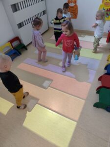 Dzieci bawią się na magicznym dywanie- biegają po kolorowych klawiszach pianina