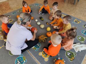 Pani opowiada o dyniach dzieciom siedzącym na dywanie