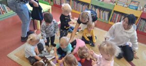 Pani z biblioteki pokazuje i czyta dzieciom książeczkę