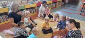 Pani z biblioteki pokazuje i czyta dzieciom książeczkę