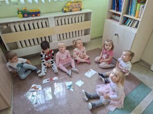 Dzieci siedzą na podłodze przy przygotowanych puzzlach