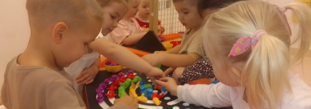 Dzieci układają tęczę z kolorowych ksztatków na stole sensorycznym