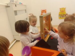 Dzieci przekładają kształtki przez siatkę przy stole sensorycznym