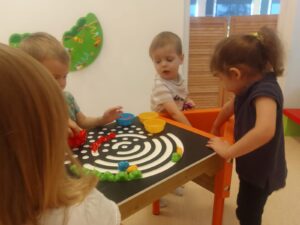 Dzieci układają tęczę z kolorowych ksztatków na stole sensorycznym