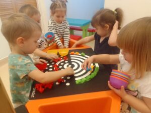 Dzieci układają tęczę z kolorowych ksztatków na stole sensorycznym